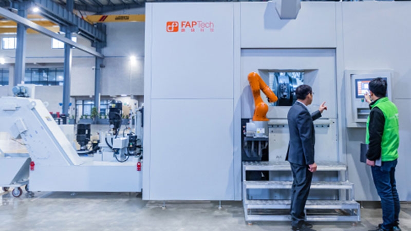 Two male employees examine machine